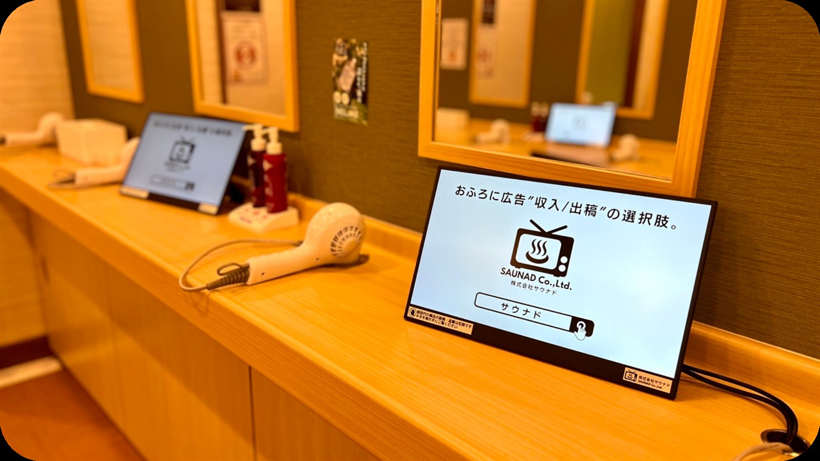 脱衣所のドライヤー前に設置したふろビジョンのデジタルサイネージ