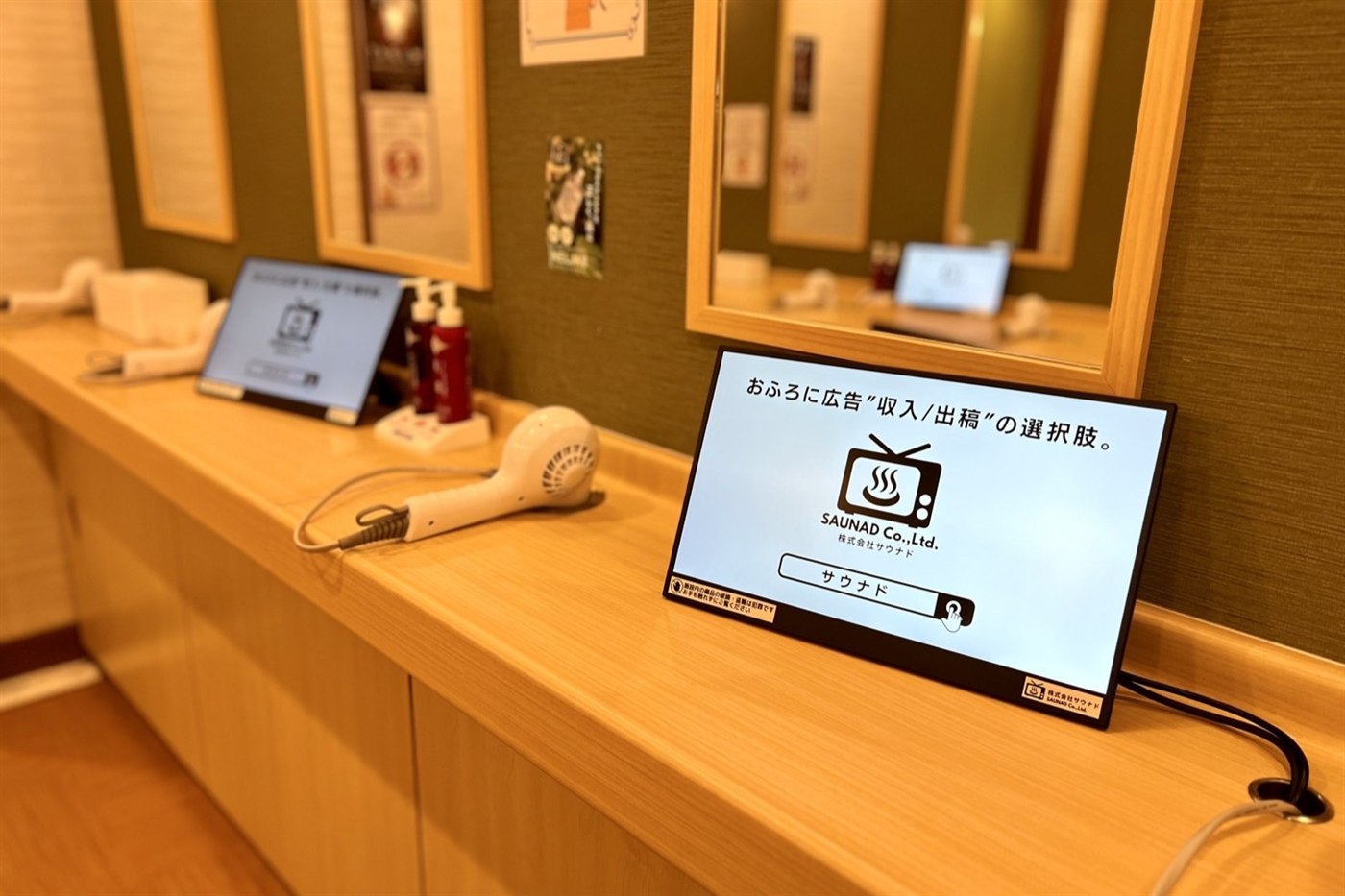 脱衣所のドライヤー前に立てかけて設置したふろビジョンのデジタルサイネージ